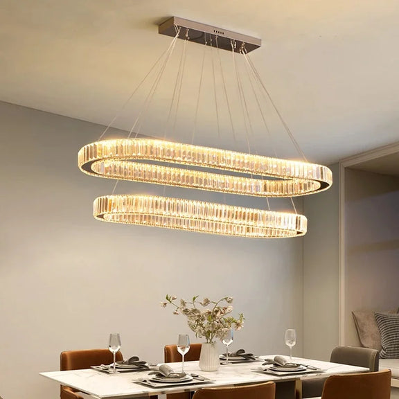 Gold crystal oval LED pendant light above dining table