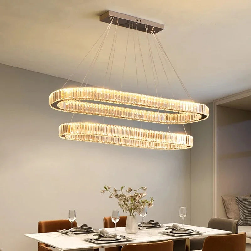 Gold crystal oval LED pendant light above dining table