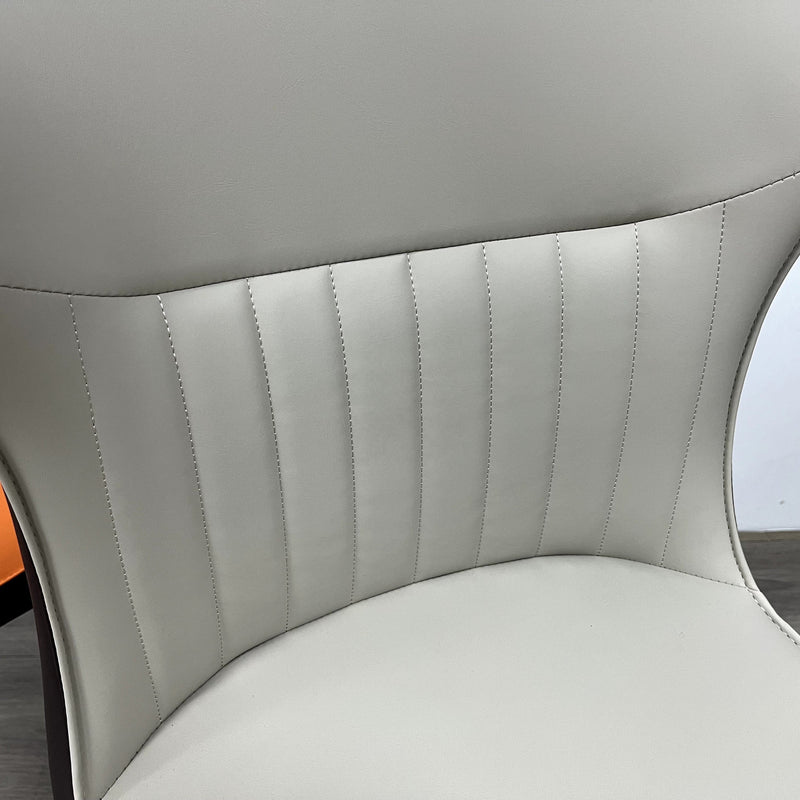 A striking chair with a terracotta leather seat, vertical stitching, and contrasting black legs