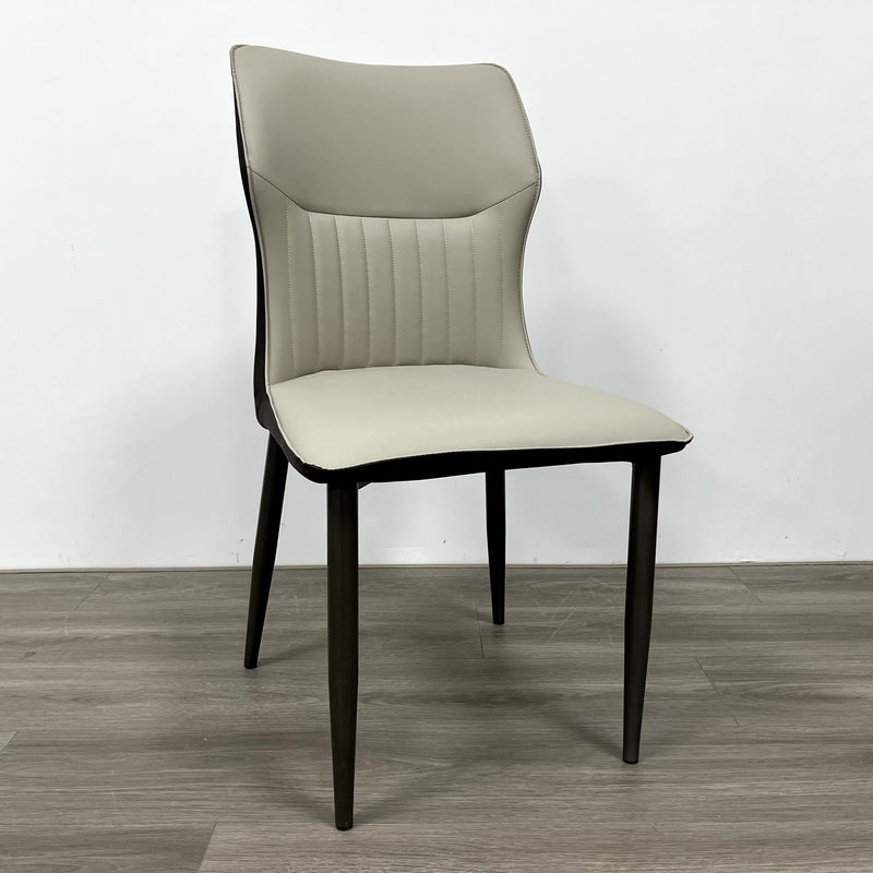 A striking chair with a terracotta leather seat, vertical stitching, and contrasting black legs