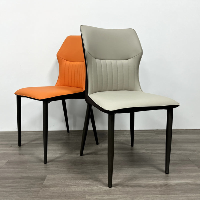 A striking chair with a terracotta leather seat, vertical stitching, and contrasting black legs